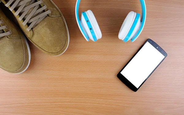 Concept with brown sneakers and wood tablet with smartphone, blue headphones