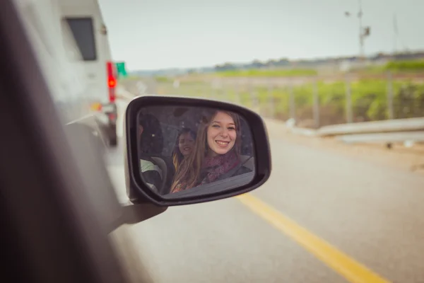 Women looking at the camera through the car side view mirror