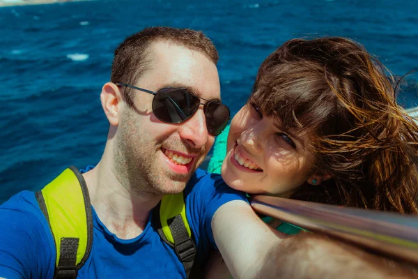 Happy couple sailing on a boat and taking selfie with smartphone