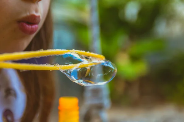 Close up of little girl blowing soap bubbles