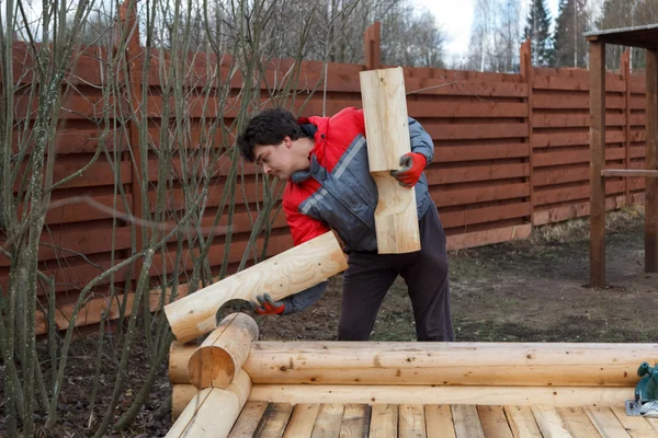 Man builds structure made of logs