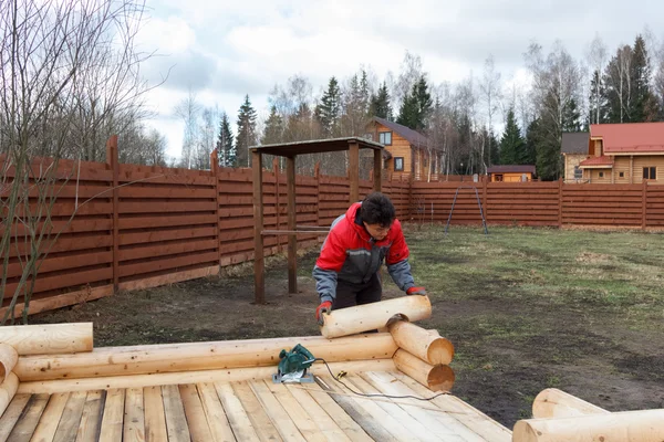 Man builds structure made of logs