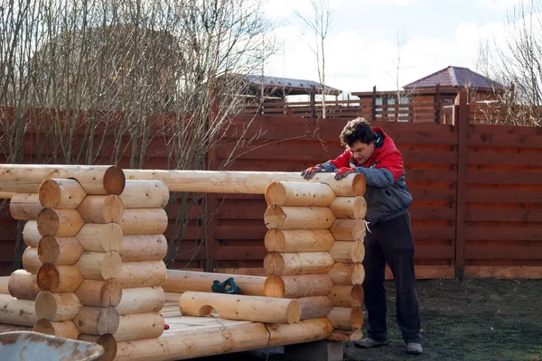 Man builds structure made of logs