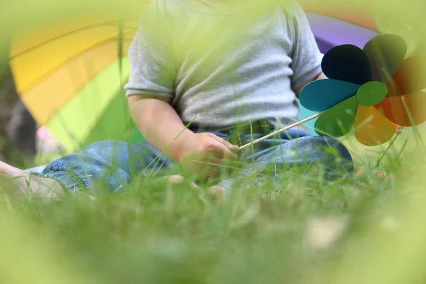 Kids feet on the grass and a toy bear on the background