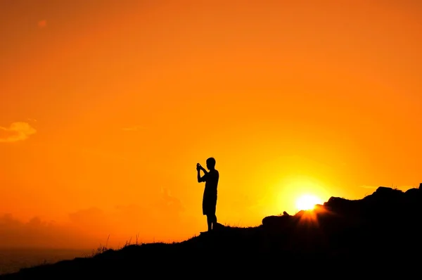 Silhouette of man on hill at sunset