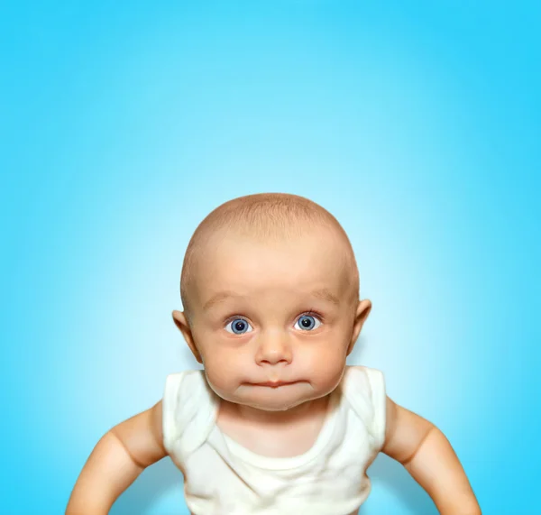 Funny portrait of an adorable baby boy sucking lips with blue eyes on background