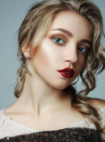 A large portrait of a very beautiful girl. girl with a professional make-up and a professional hair styling. girl with red lips, big eyes on a gray background.