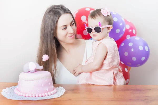 Mother with funny baby celebrating first birthday. Cake.