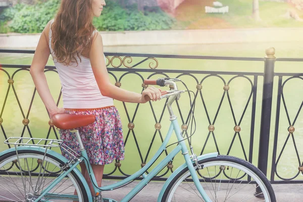 Young girl standing near fence near vintage bike at park