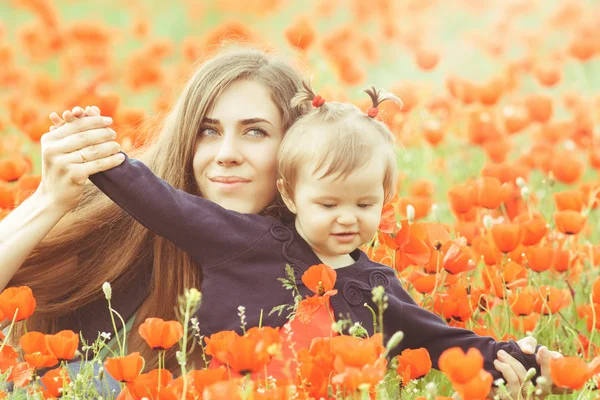 Mother with funny child outdoor at poppy flowers field