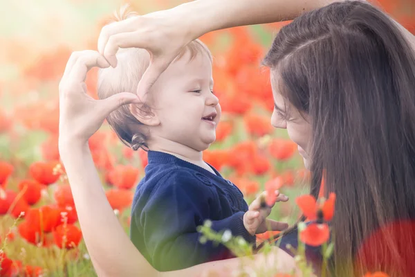 Mother with funny child outdoor at poppy flowers field