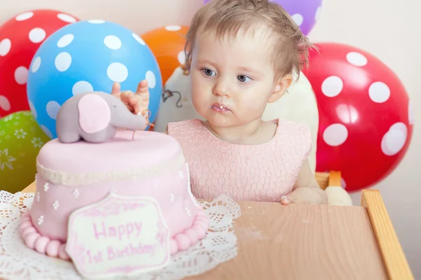 Cute baby celebrating first birthday and eating cake.