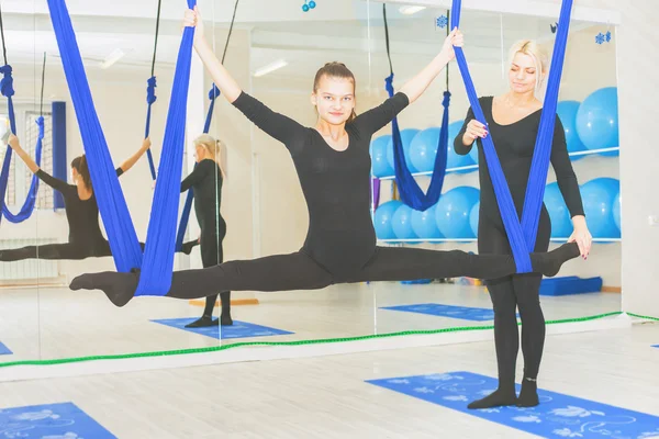 Young women doing aerial yoga exercise or antigravity yoga