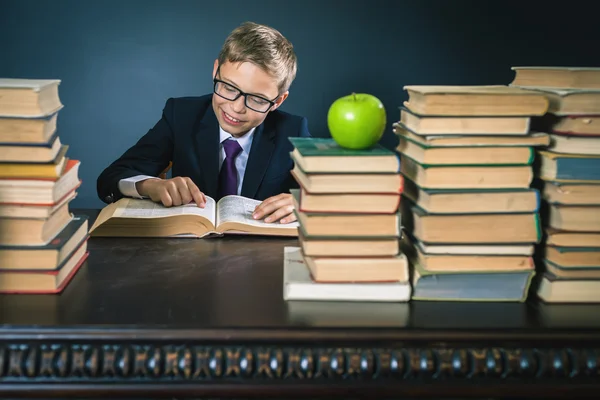 Smart school boy reading a book at library