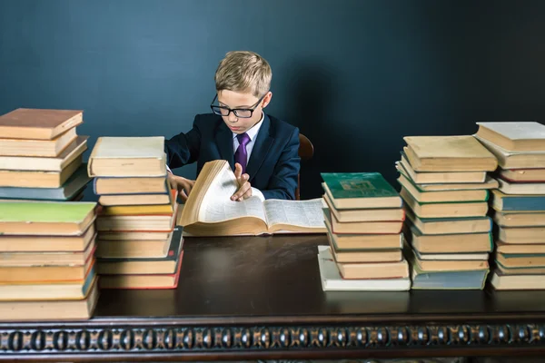 Smart school boy reading a book at library