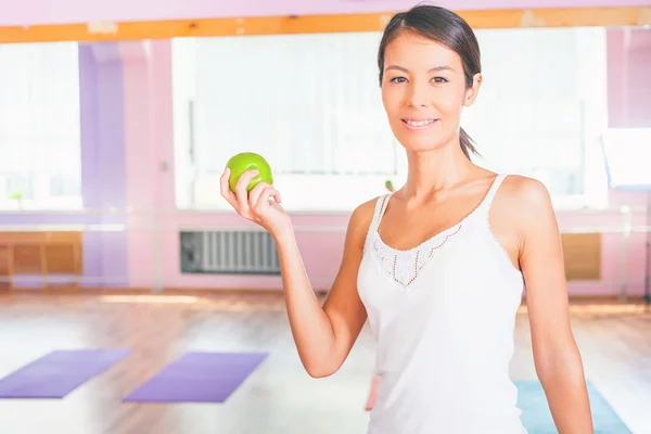 Beautiful asian woman after fitness exercise holding green apple
