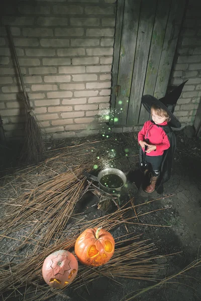 Little witch making a magic potion at Halloween night. Horror.