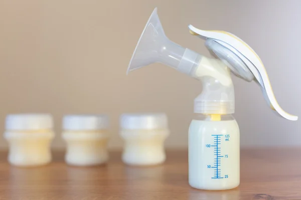 Manual breast pump and milk at background