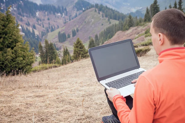 Man uses laptop remotely at mountain