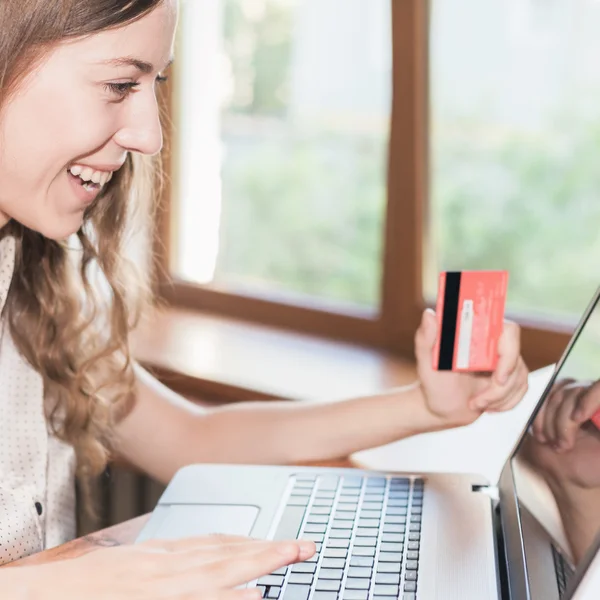 Beautiful successful woman holding credit card, and shopping through laptop