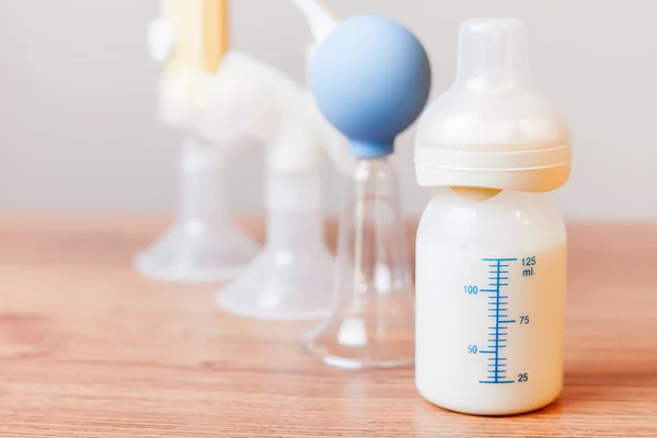 Manual breast pump and milk at background