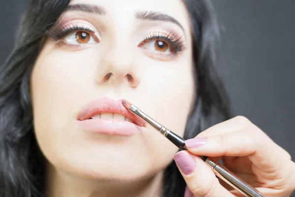 Specialist in beauty salon gets lipstick, lip gloss, professional make-up.