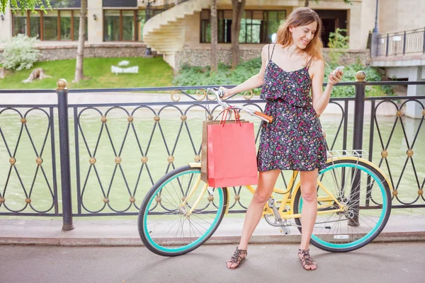 Pretty woman with bugs using mobile phone near vintage bicycle