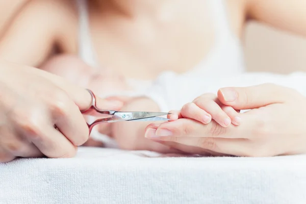 Mom tonsured nails on the hands newborn using nail scissors