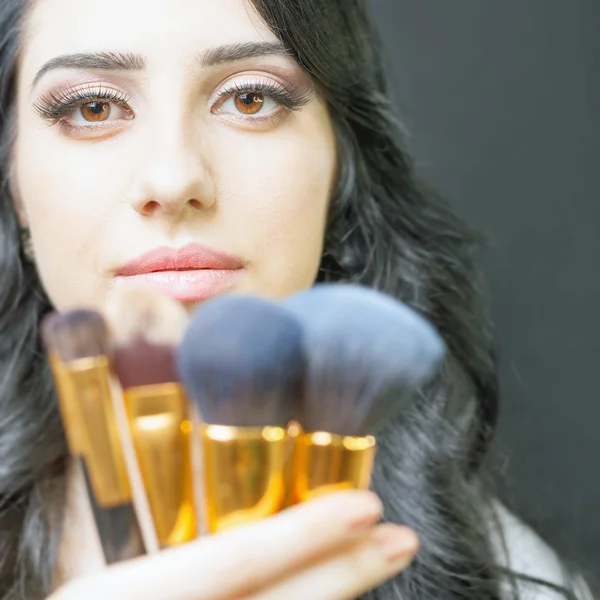 Beautiful woman at beauty salon with set of makeup brushes