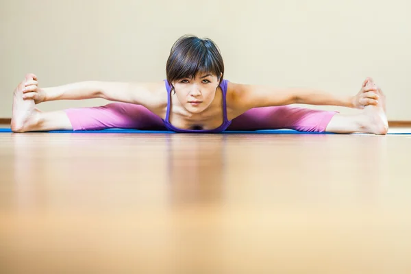 Asian woman doing splits for yoga exercise indoor