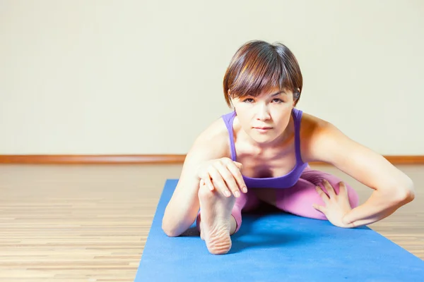 Asian woman stretching at mat before yoga exercise indoor