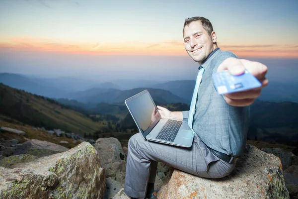 Successful businessman on top of mountain, using a laptop