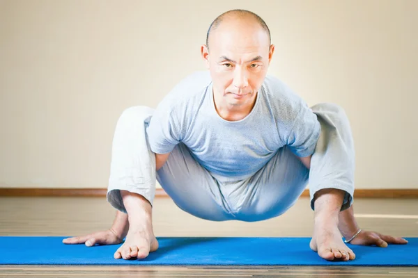 Inspired asian man doing exercise of yoga indoor