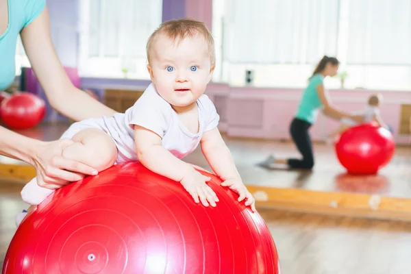 Mother with happy baby doing exercises with gymnastic ball