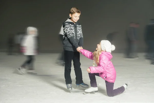 Happy children ice skating at ice rink, winter night