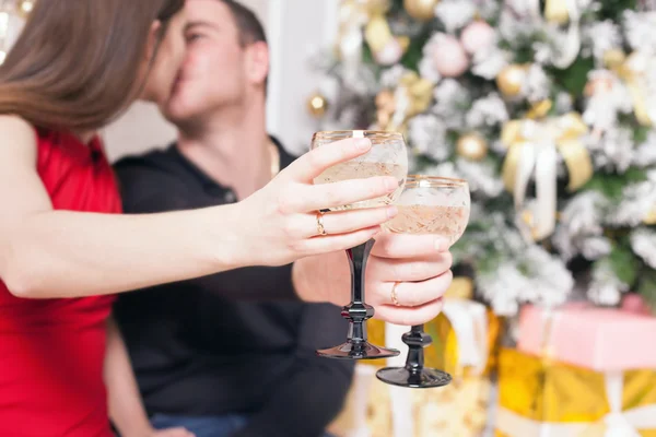 Beautiful happy couple celebrating New Year, holding glasses of champagne