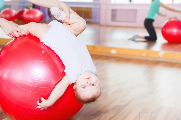 Mother with happy baby doing exercises with gymnastic ball