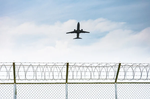 Airplane taking off from the airport over the fence of high security zone