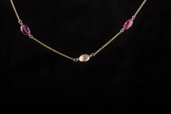 Gold necklace with precious stones on a black background