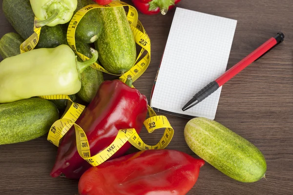 Fresh vegetables with a tape measure on a wooden background as a symbol of healthy eating