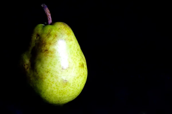 Green pear on black background