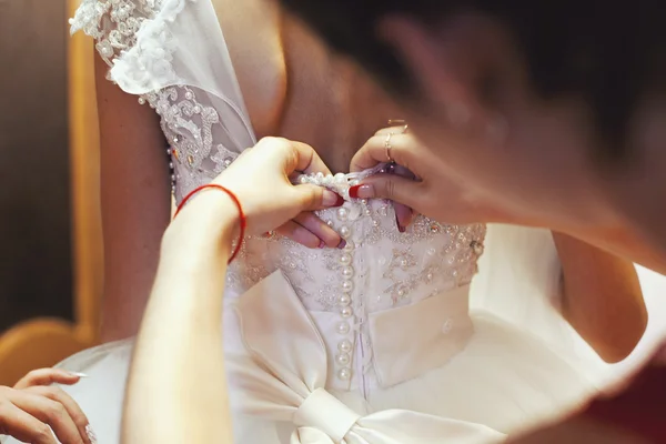 Bridesmaid helping put on wedding lace dress