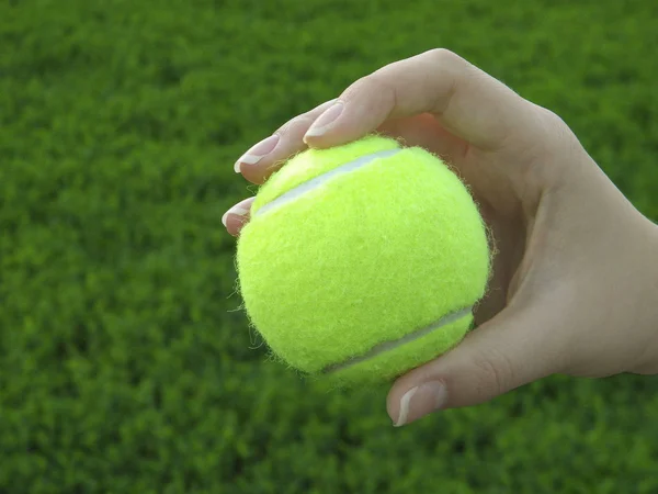 Yellow tennis ball in female hand