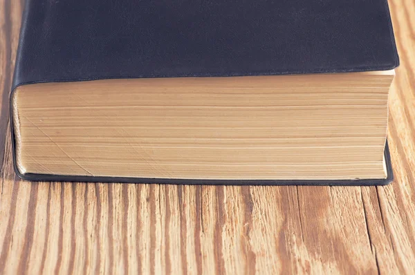 Old book lower edge and part of cover on old rustic wooden table