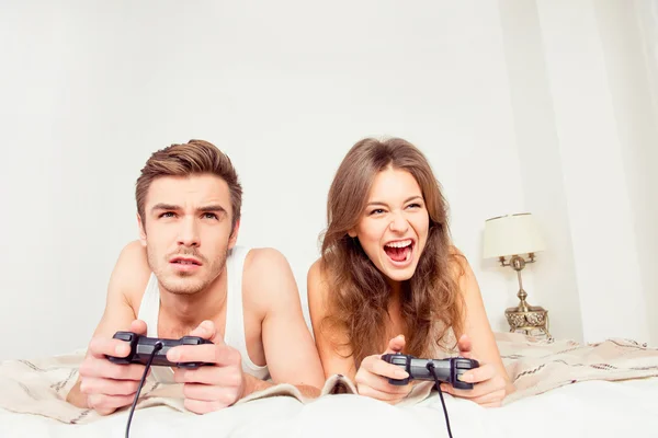 Happy couple in love playing video games with joysticks on the b