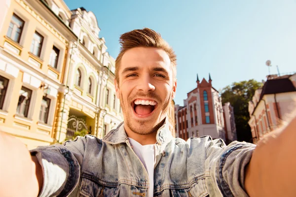 Cheerful happy man making selfie photo on the street