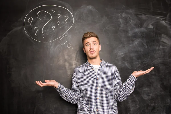 Young freelancer at a loss on the background of chalkboard