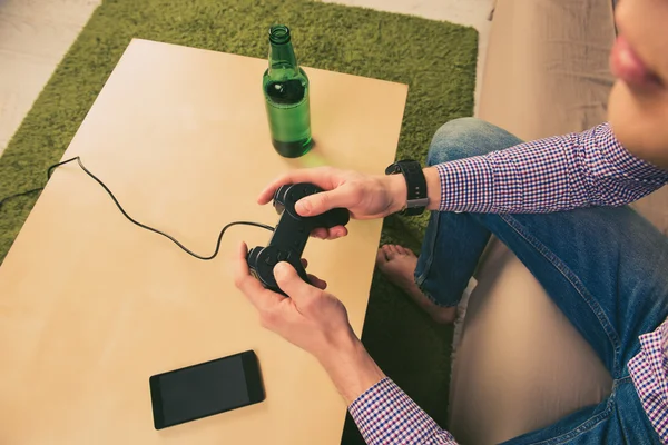 Close up photo of man playing video games with beer