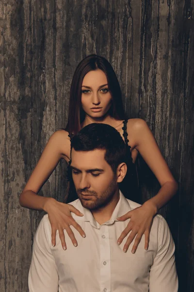 Sexy young  woman lying her hands on shoulders of her boyfriend
