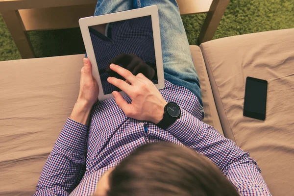 Close up top view photo of man sitting on sofa with tablet